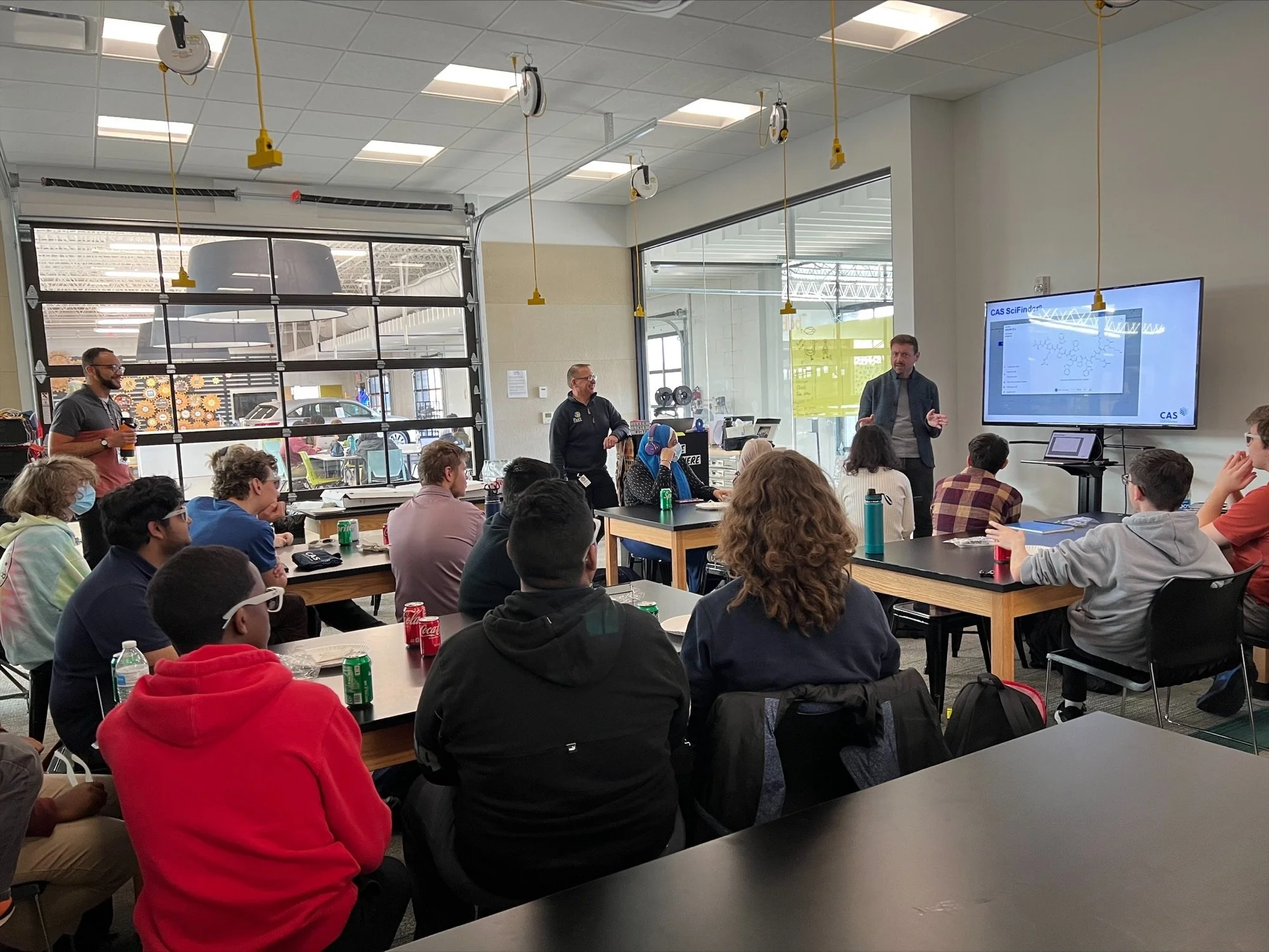 Students in a classroom presentation with an instructor presenting on a large screen